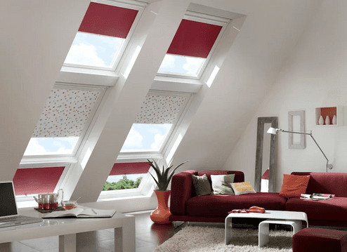 Plissees an Dachschrägenfenstern Dachschrägenfenster mit roten und gemusterten Plissees neben Wohnzimmerbereich